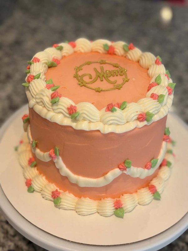 Peach buttercream cake with cream shell border and gold "Mom" topper