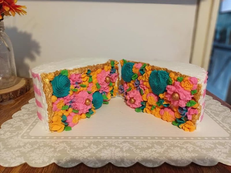 White cake cut open to reveal densely piped flowers inside