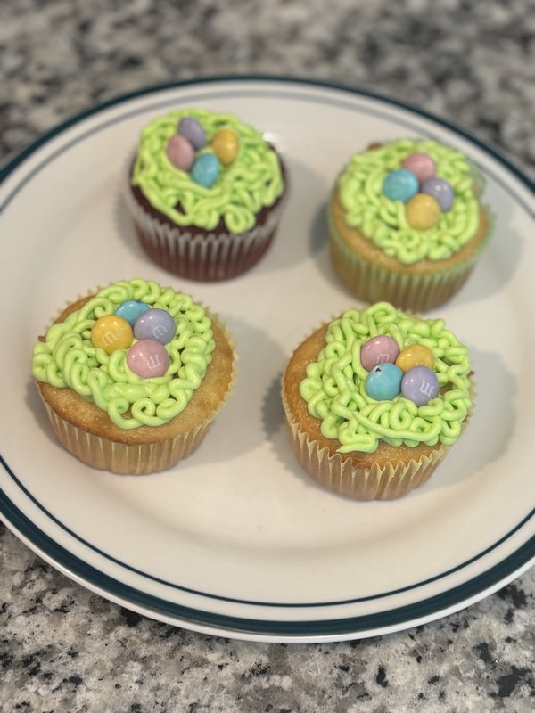 Cupcakes piped with green grass nests filled with pastel candy eggs