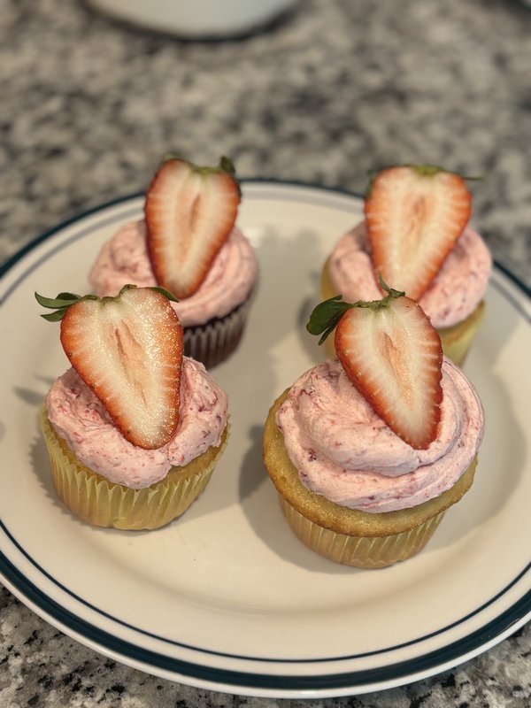 Pink strawberry buttercream cupcakes with fresh strawberry halves