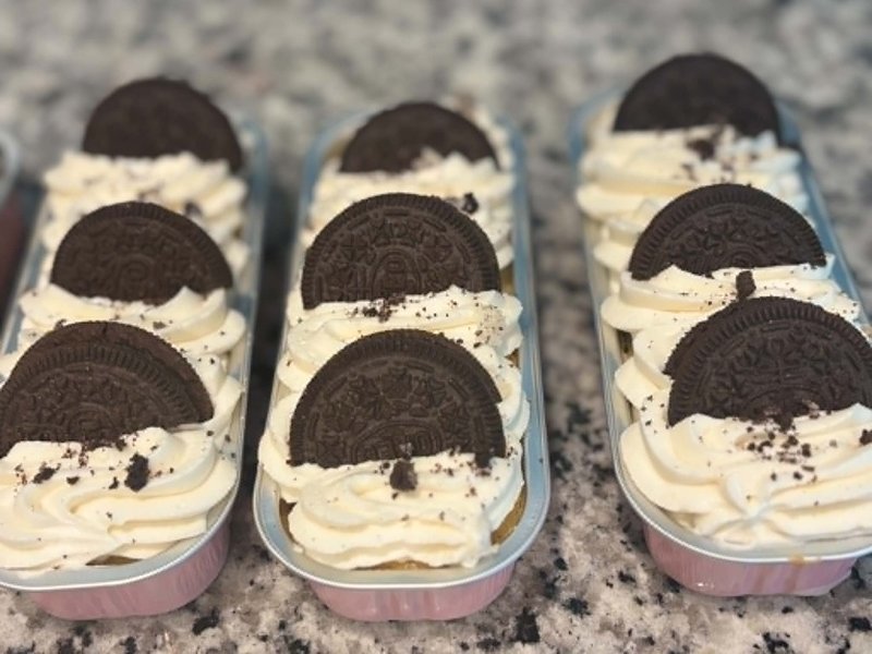 Row of classic Oreo dessert cups with white frosting, half-Oreos, and chocolate crumble