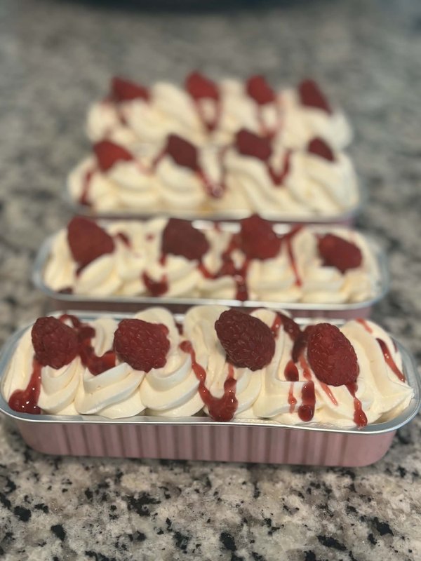 Raspberry dessert cups with swirled cream, fresh raspberries, and berry drizzle