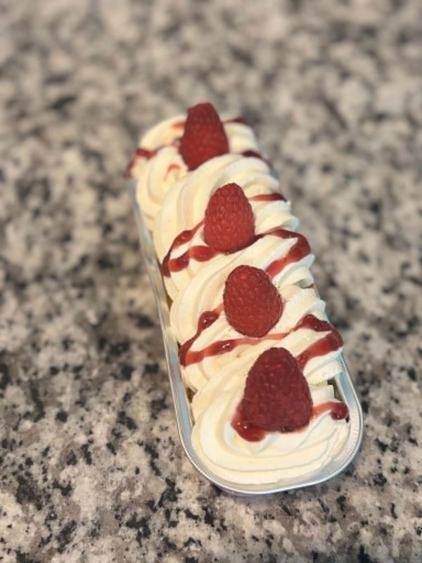 Single-serve raspberry eclair with cream swirl, fresh raspberries, and berry coulis